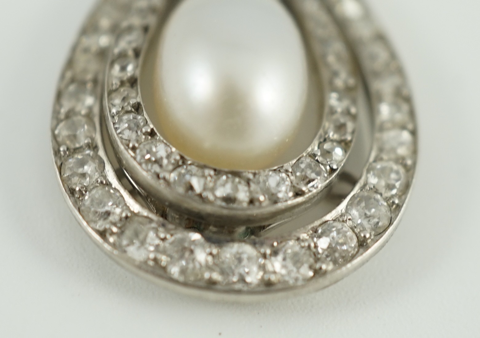 An early 20th century platinum, cultured? pearl and diamond cluster set pear shaped drop pendant necklace